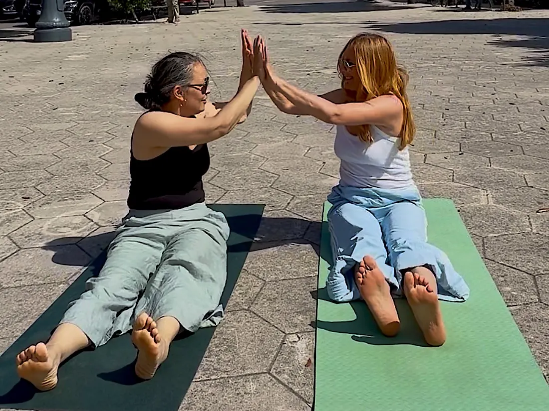 Sonia und Jeanna sitzen auf ihren Matten und klatschen sich ab