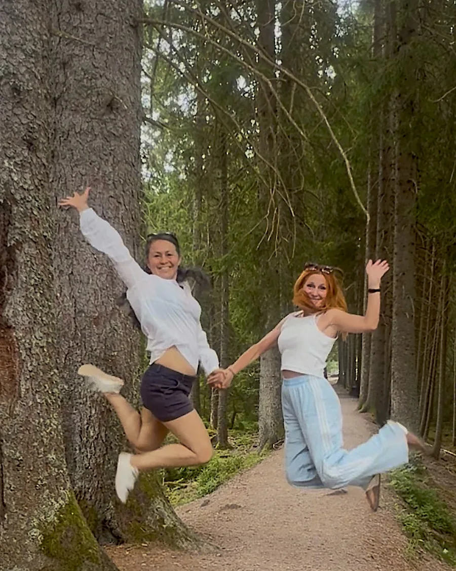 Sonia und Jeanna springen lachend Hand in Hand in die Luft